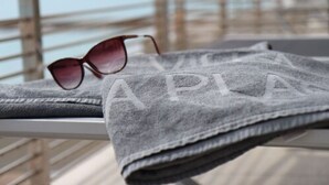 A towel with the word "A PLAN" on it, sunglasses, and a railing in the background. - Hotel Villa Azur (Villeneuve-Loubet)