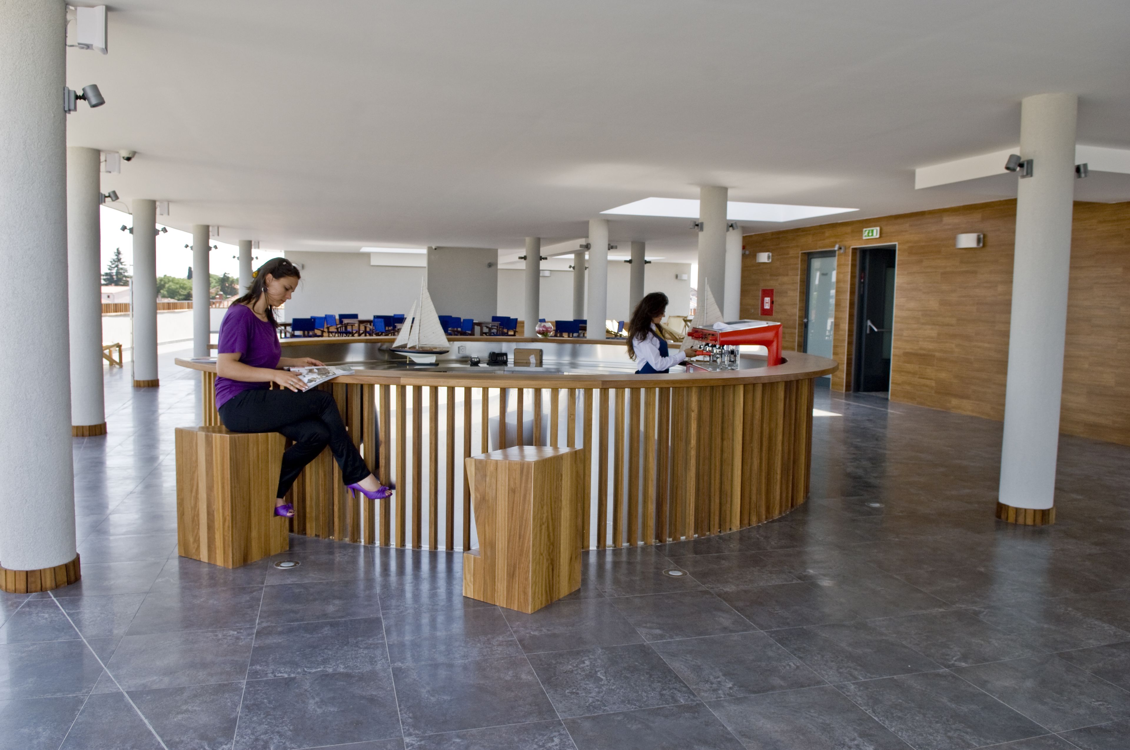 A modern reception area with a wooden reception desk, a seating area, and a view of the outdoors.
