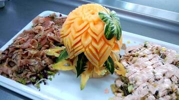 A plate with three different dishes: a salad with shredded meat, a carved melon, and a creamy chicken salad.