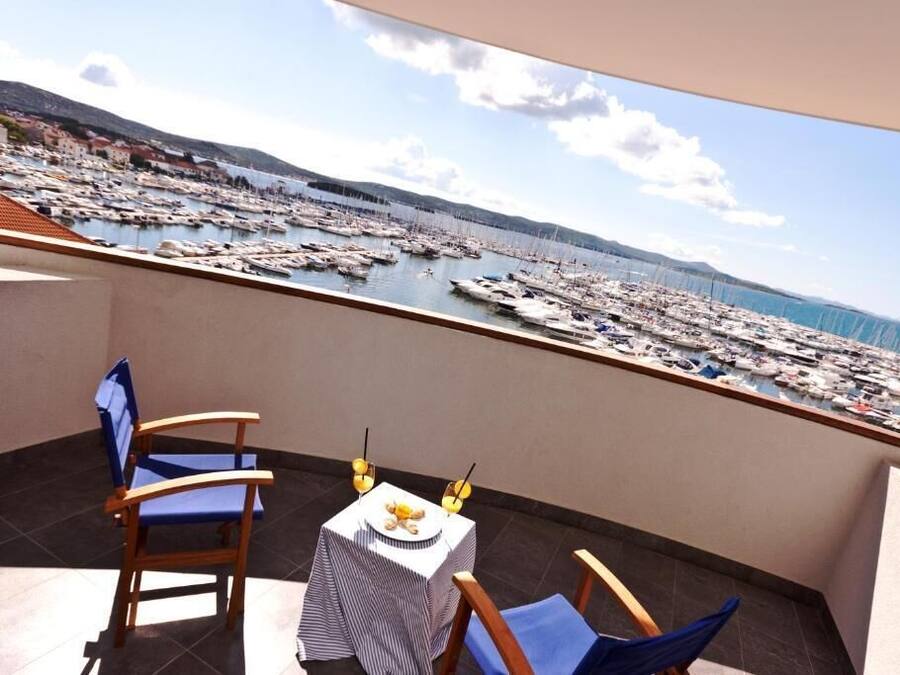 A balcony with two chairs and a table, overlooking a marina with numerous boats.