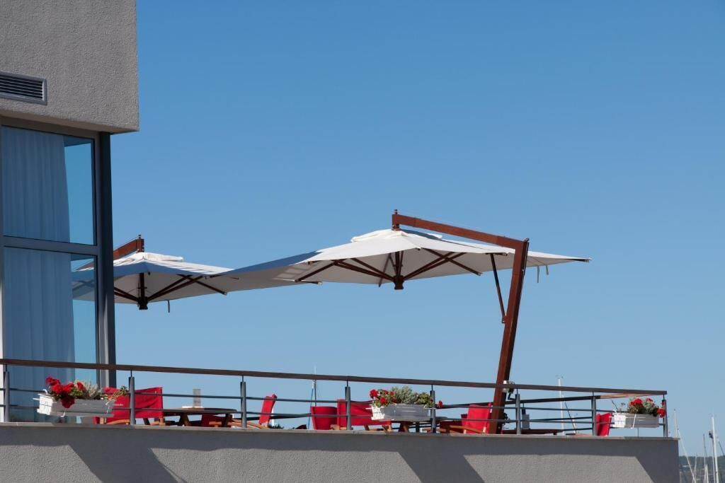 Un balcón con mobiliario exterior y sombrillas, con vista a una masa de agua.