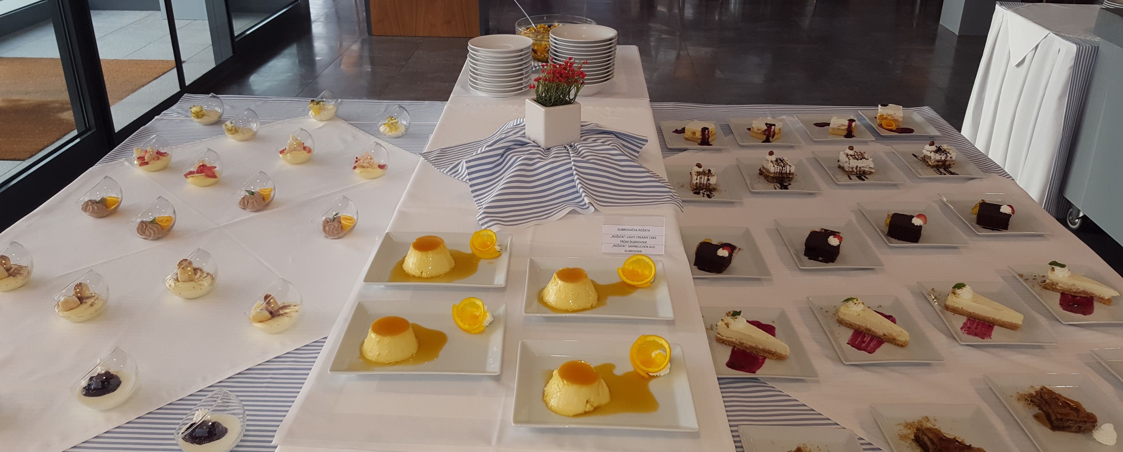 A dessert buffet with various plated sweets and a floral centerpiece.