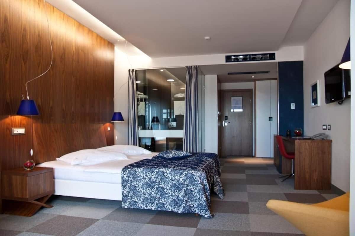 A modern hotel room with a large bed, a desk, and a seating area.