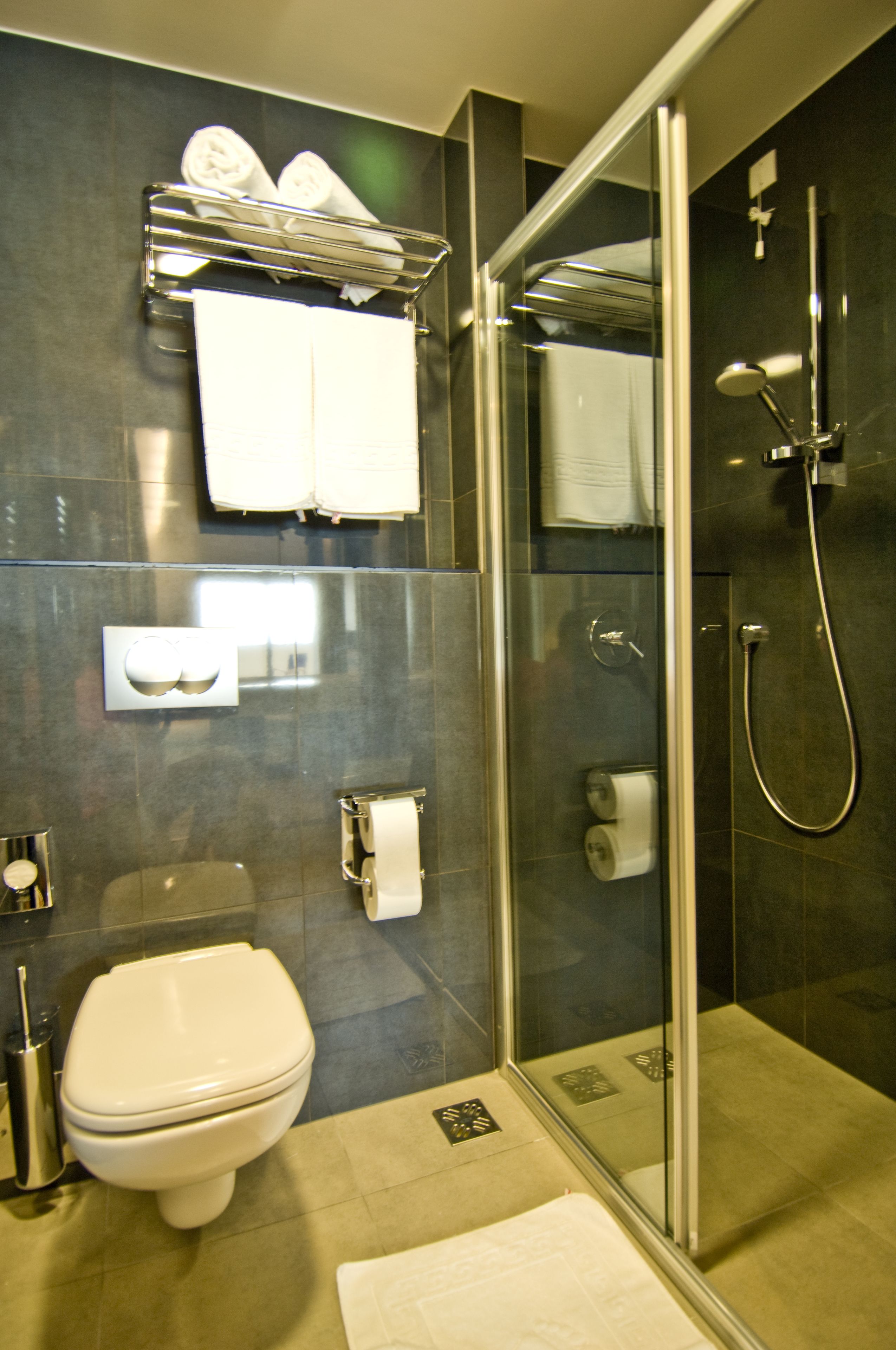 Un baño moderno con ducha de vidrio, inodoro y perchero para toallas.