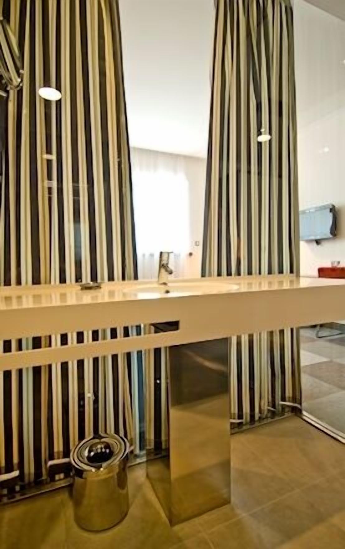 Un baño moderno con cortinas a rayas, un espejo grande y un lavabo.