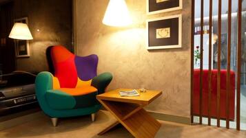 Una sala de estar moderna con un sillón azul turquesa, una mesa de centro de madera y un sofá rojo.