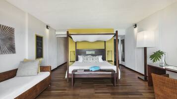 A spacious room with a large bed, a sofa, and a bedside table with a lamp.