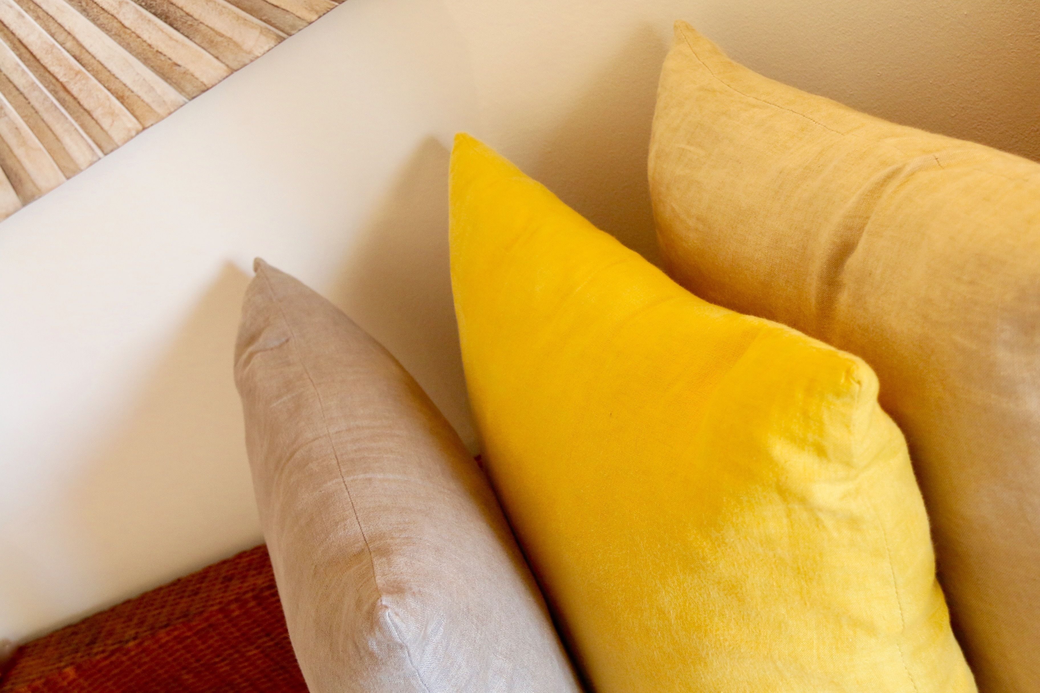 A close-up of a white pillow with a yellow pillow and a beige pillow.