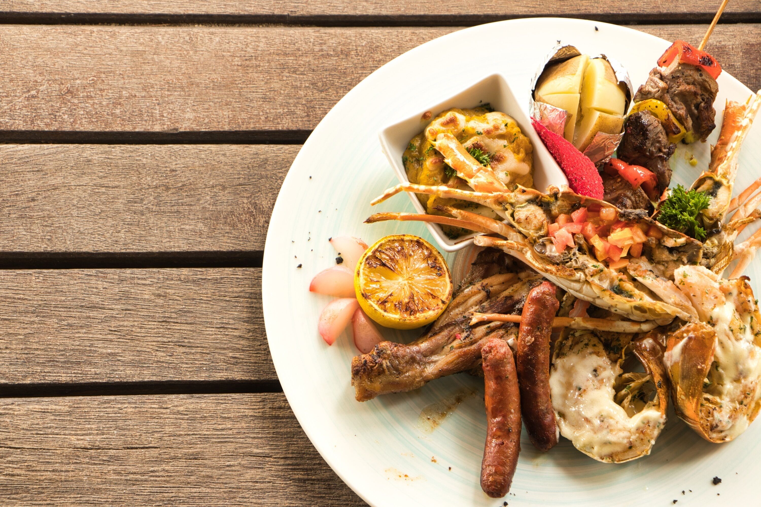 Prato com mariscos e carnes sobre uma mesa de madeira.