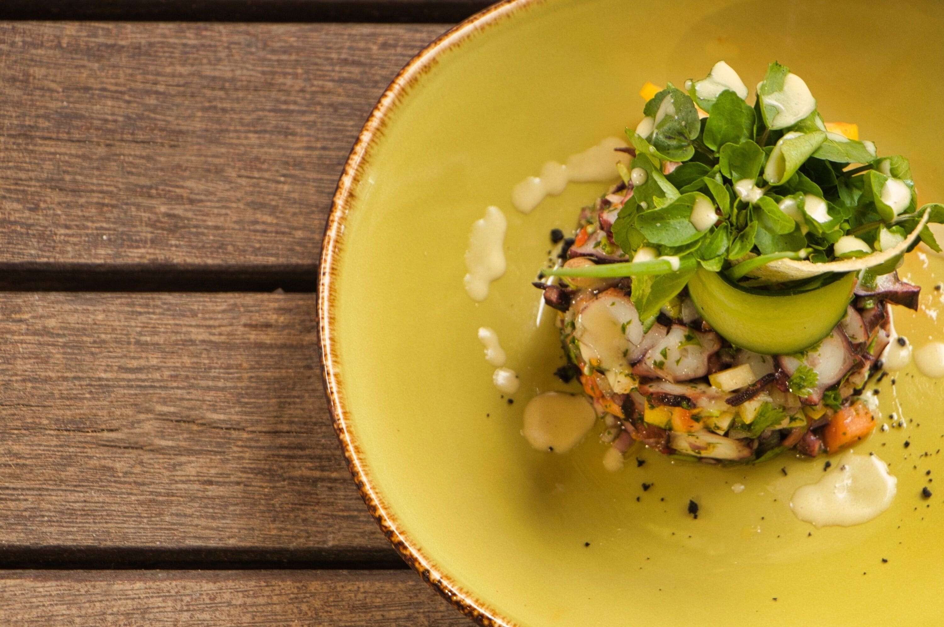 A dish on a yellow plate with a wooden background.