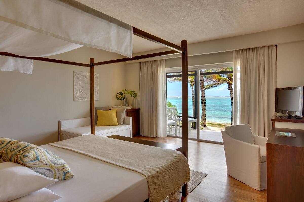 Une chambre d’hôtel avec un lit, un bureau, une chaise et une vue sur l’océan.