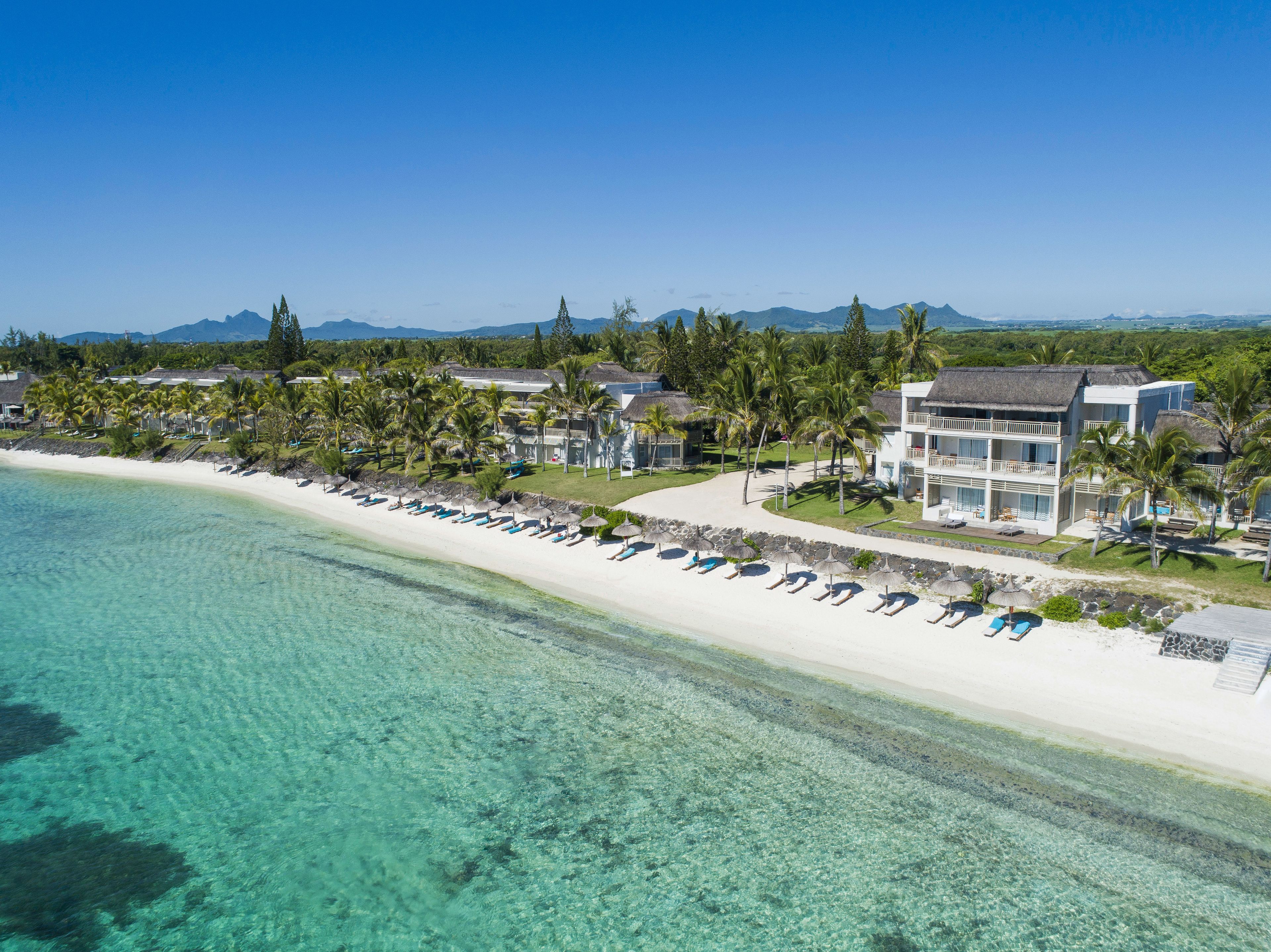 A beachfront resort with multiple villas, a sandy beach, and clear turquoise waters.
