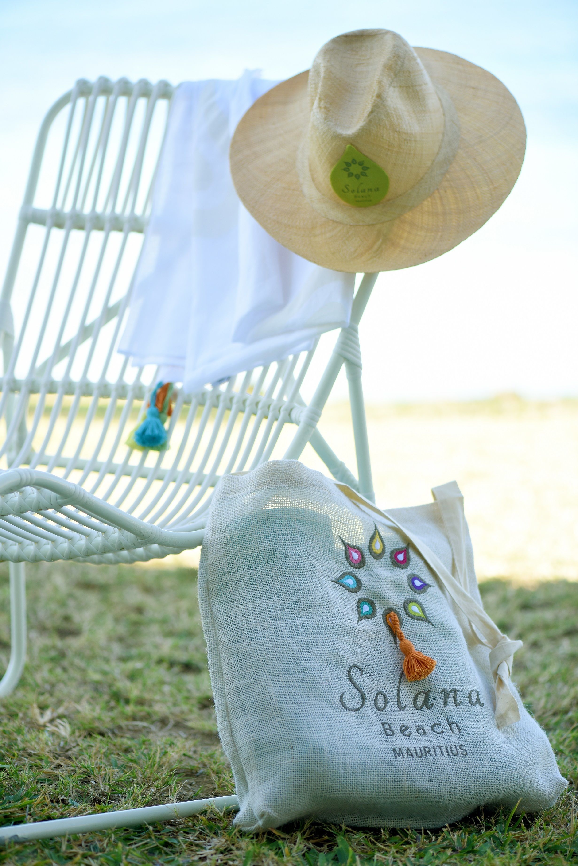 Una silla de playa con un sombrero de paja y un bolso de playa que dice 'Solana Beach Mauricio'.