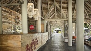 Un área de recepción con mostrador de madera, pared de piedra y techo de paja.