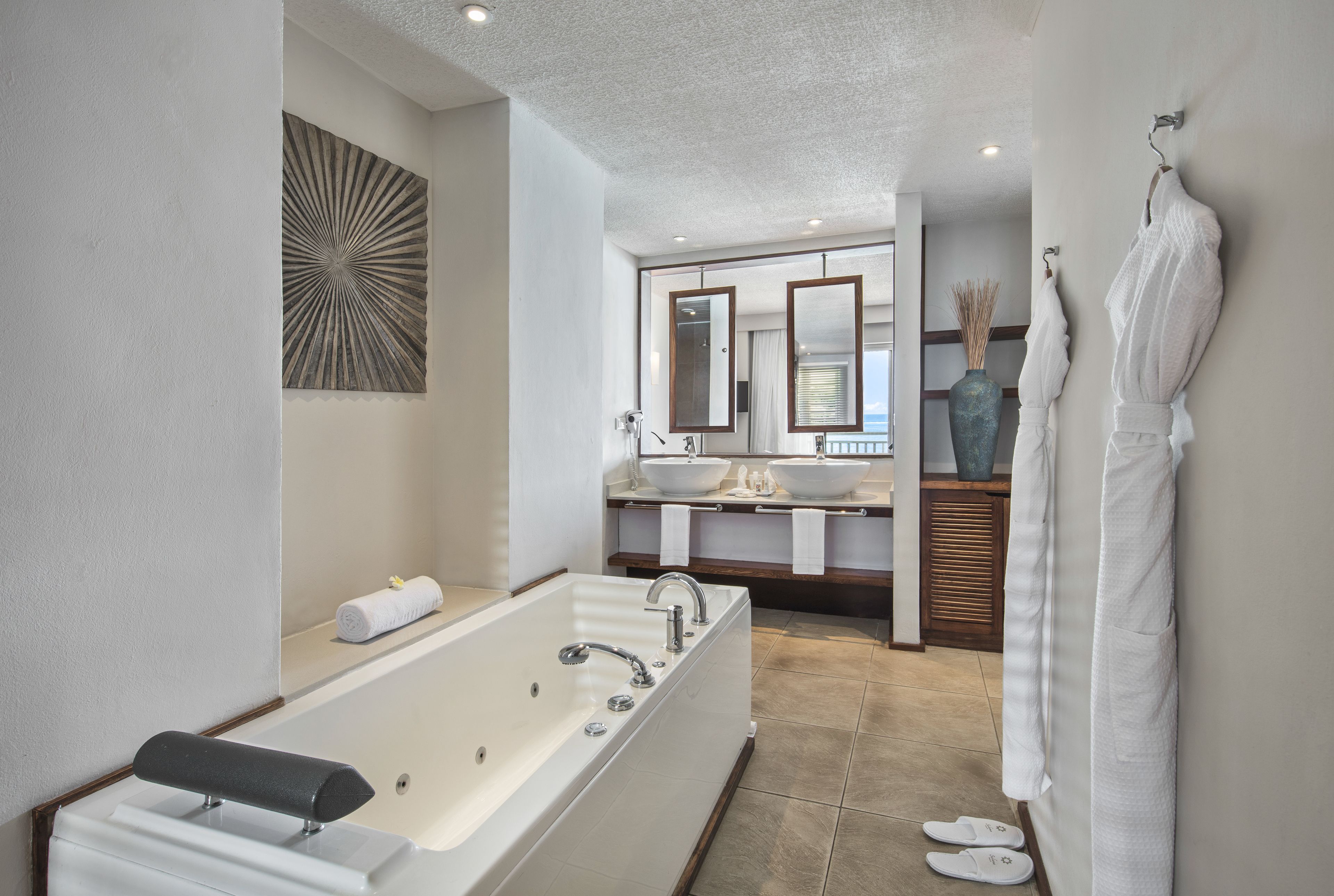 A modern bathroom with a large bathtub, two sinks, and a mirror.