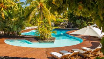 Relax by the serene pool surrounded by lush greenery and a wooden deck.