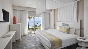 Une chambre d’hôtel avec un lit, une table de chevet, une télévision et une vue sur l’océan.