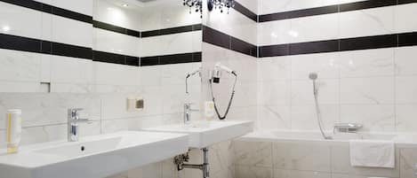 A modern bathroom with two sinks, a bathtub, and a shower.