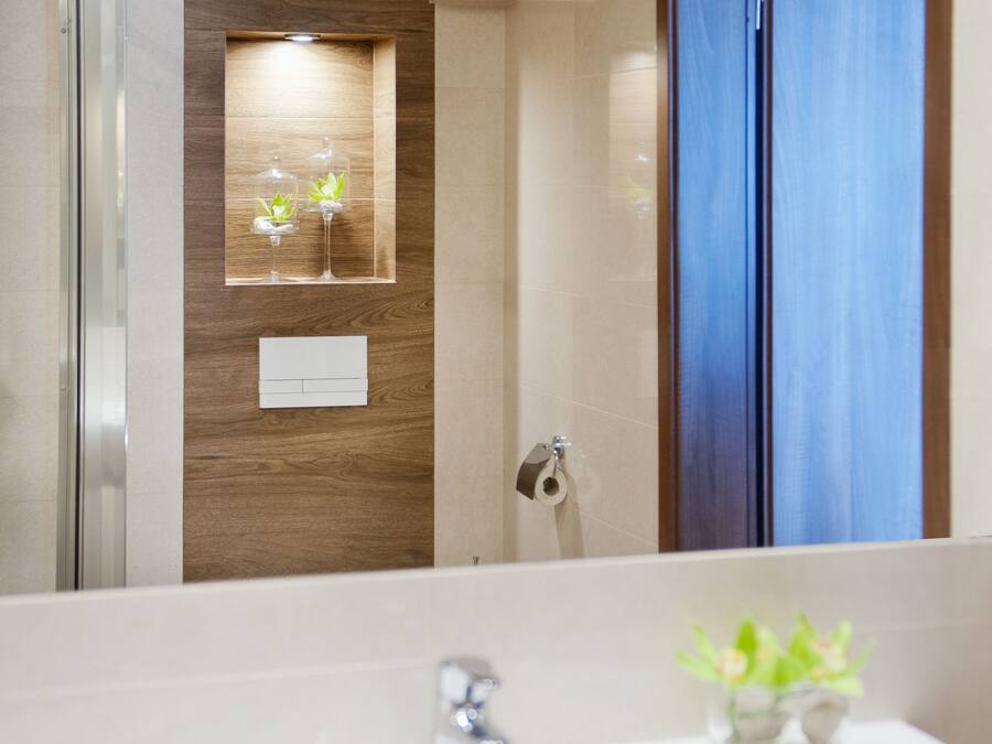 Une salle de bain avec un grand miroir, un lavabo et un mur d’accent en bois.
