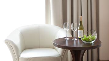 Una silla de cuero blanco y una mesa redonda de madera con dos copas de vino y una botella.