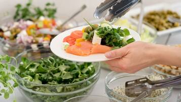 A buffet with various dishes including a plate of salmon, mixed vegetables, and salads.