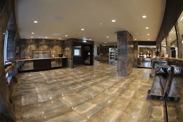 A spacious lobby with a polished tile floor, a reception desk, and a large mirror reflecting the interior.