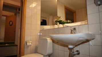 A bathroom with a white toilet, a sink, and a mirror.