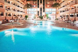 Una piscina al aire libre, sombrillas, sillones reclinables de piscina