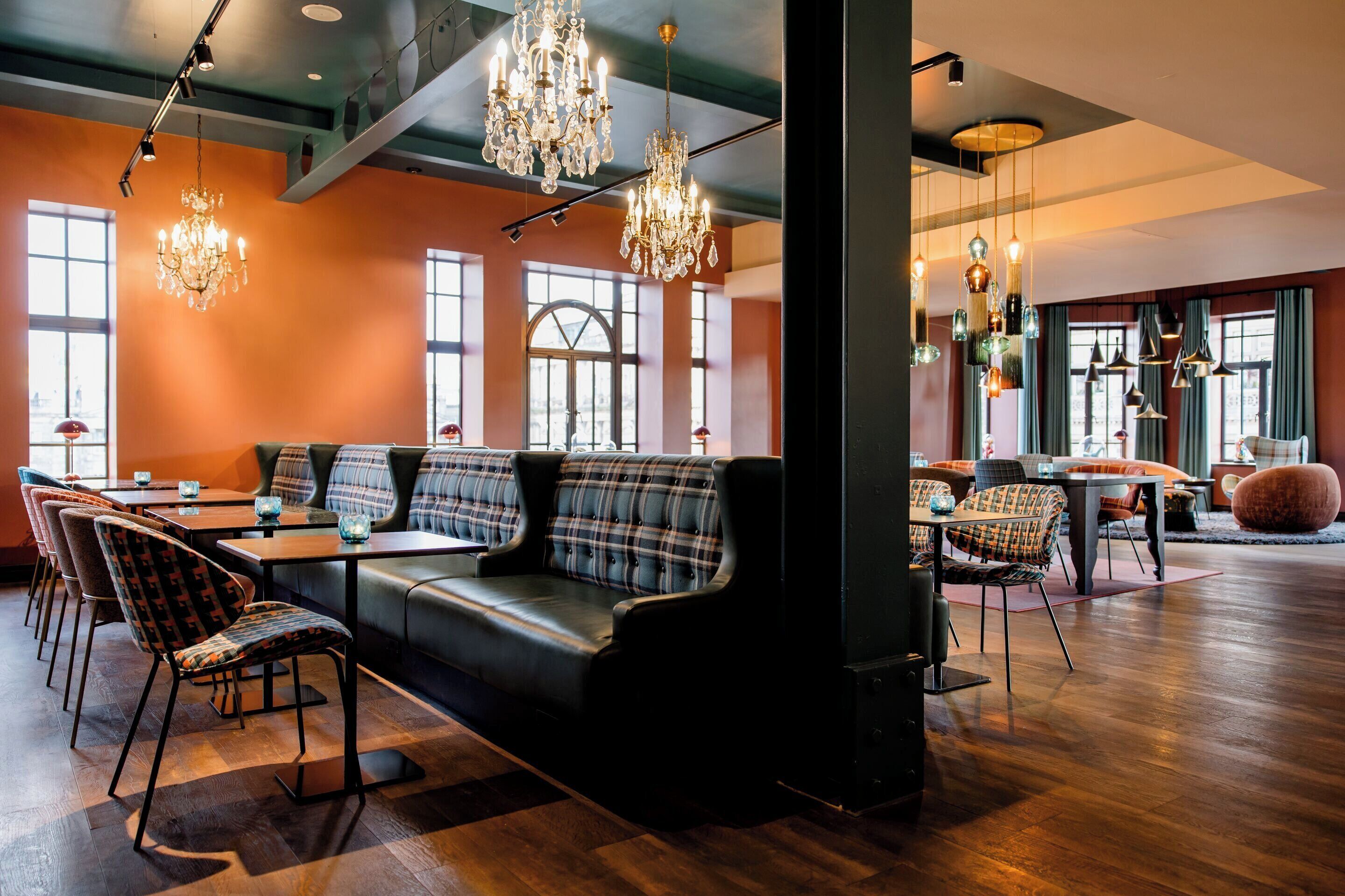 A modern interior with a black leather sofa, plaid chairs, and a wooden floor.