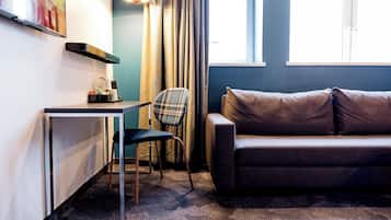 Una habitación moderna con sofá, una mesita, una silla y televisor montado en la pared.