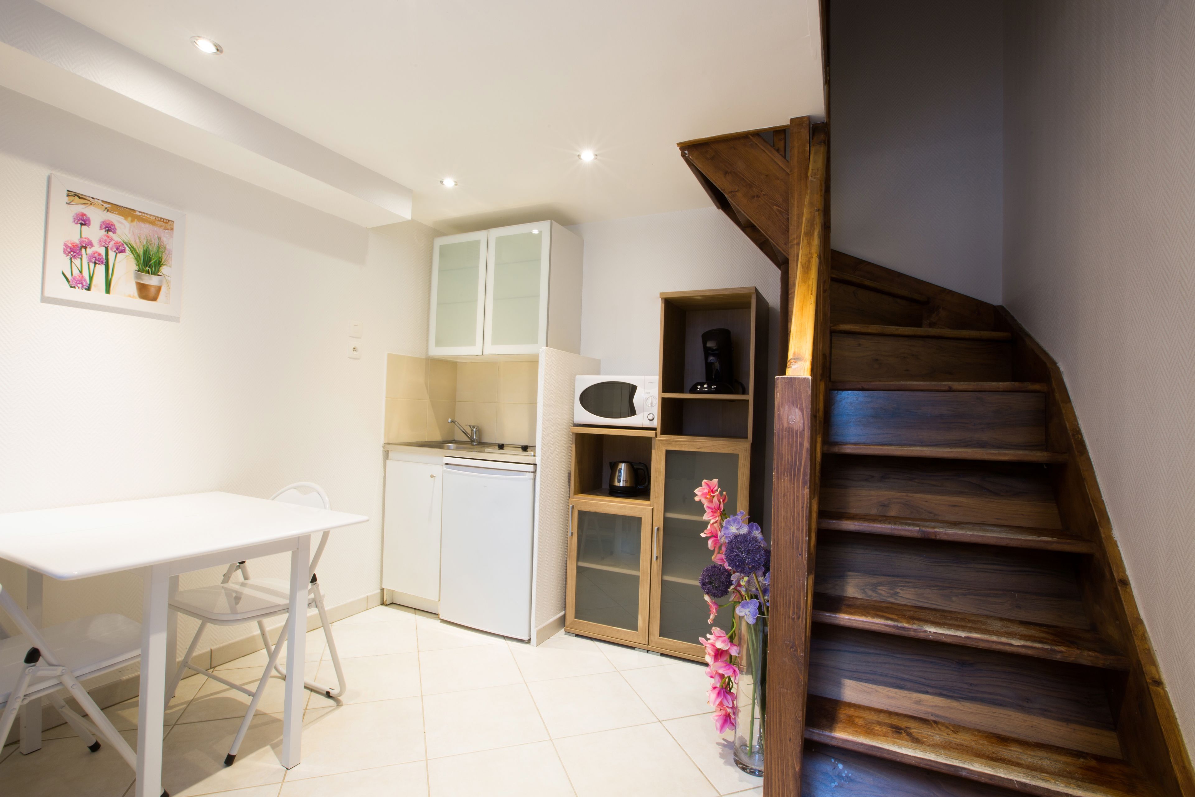 A compact kitchen with white cabinets, a microwave, and a small dining area with a white table and chairs.