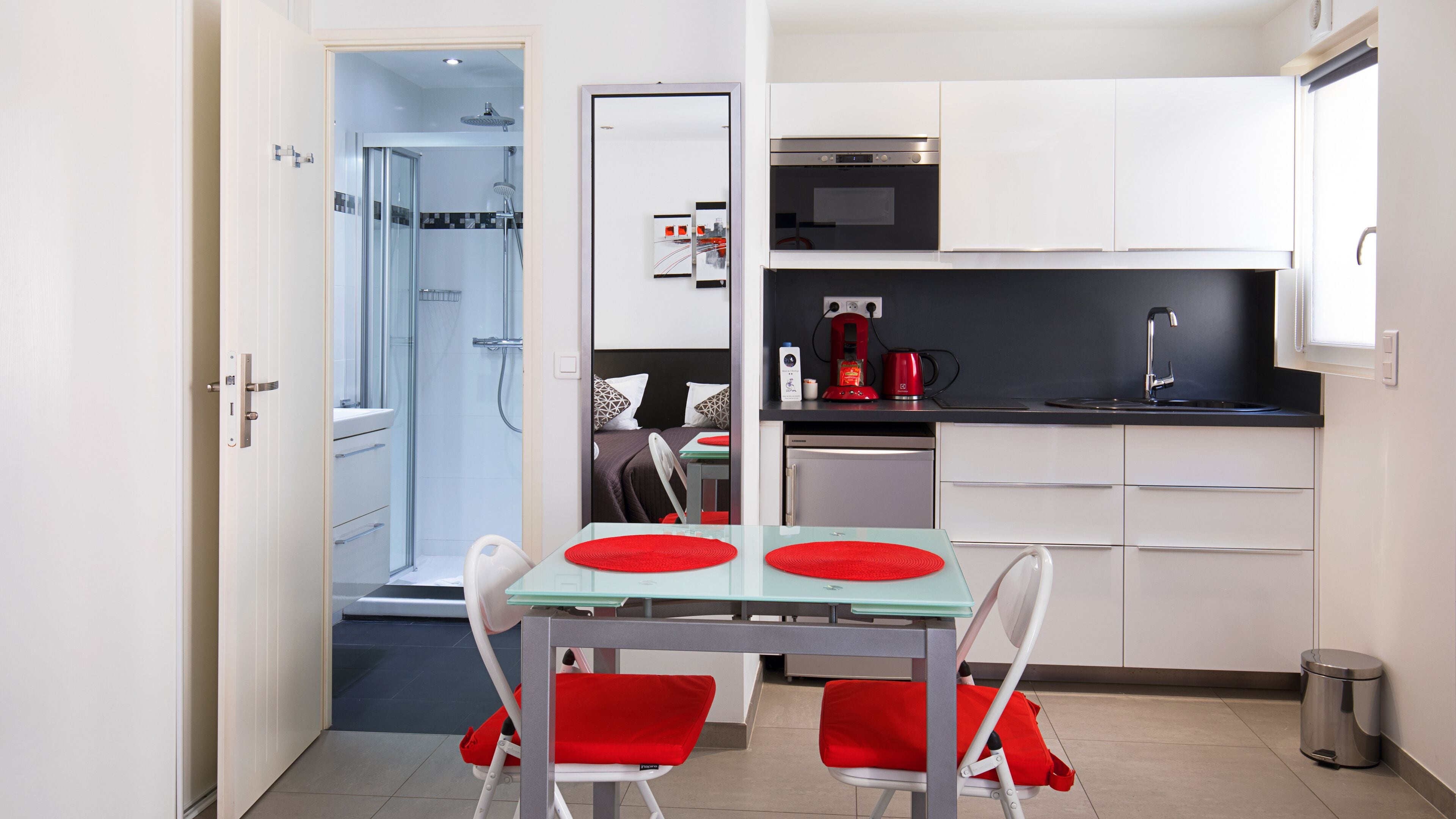A compact kitchen with white cabinets, a microwave, and a coffee machine.