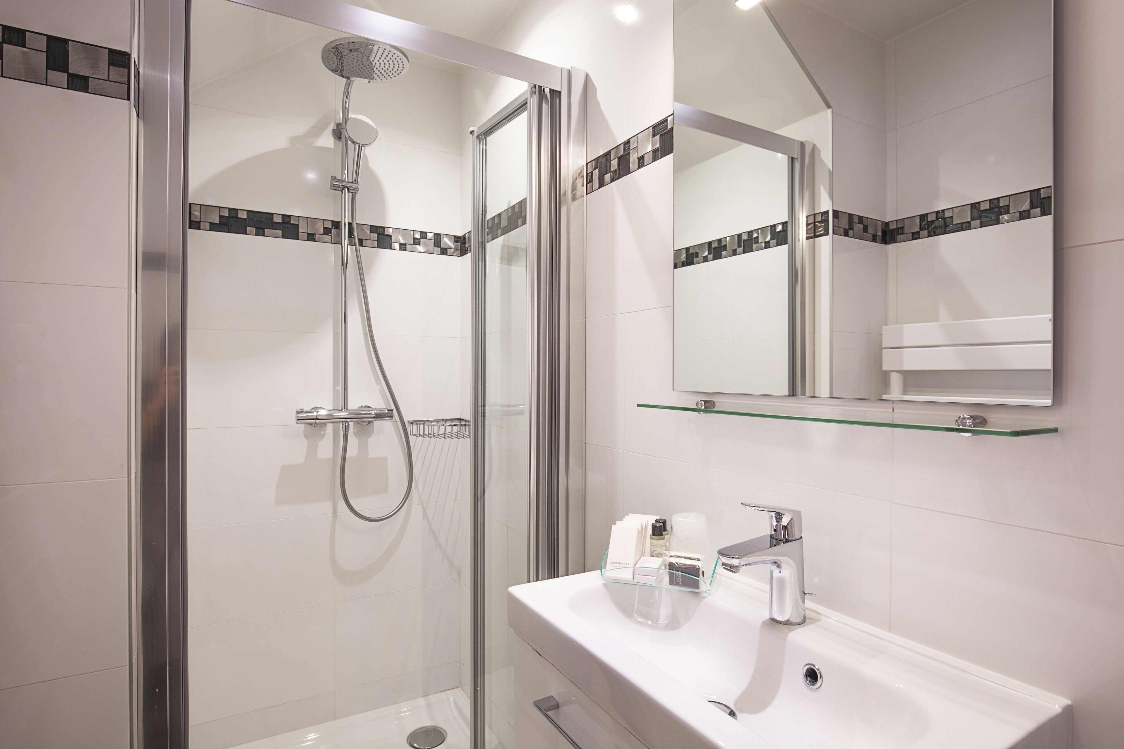 A modern bathroom with a glass-enclosed shower, a white sink, and a mirror above the sink.