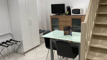 Une pièce compacte comprenant un coin cuisine, une table à manger avec des chaises, un canapé et une armoire.