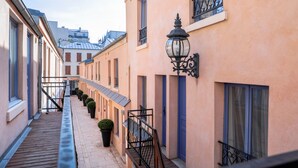 A narrow alleyway with buildings on either side, featuring balconies with black railings and a street lamp. - Hôtel de L'Horloge (Paris)