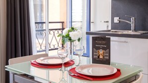 A hotel room with a glass table set for two, a vase with white flowers, and a sign indicating the hotel is located in Paris. - Hôtel de L'Horloge (Paris)