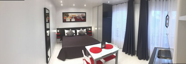 Un dormitorio moderno con una cama, una mesita de noche, un espejo, un cuadro y una ventana con cortinas.