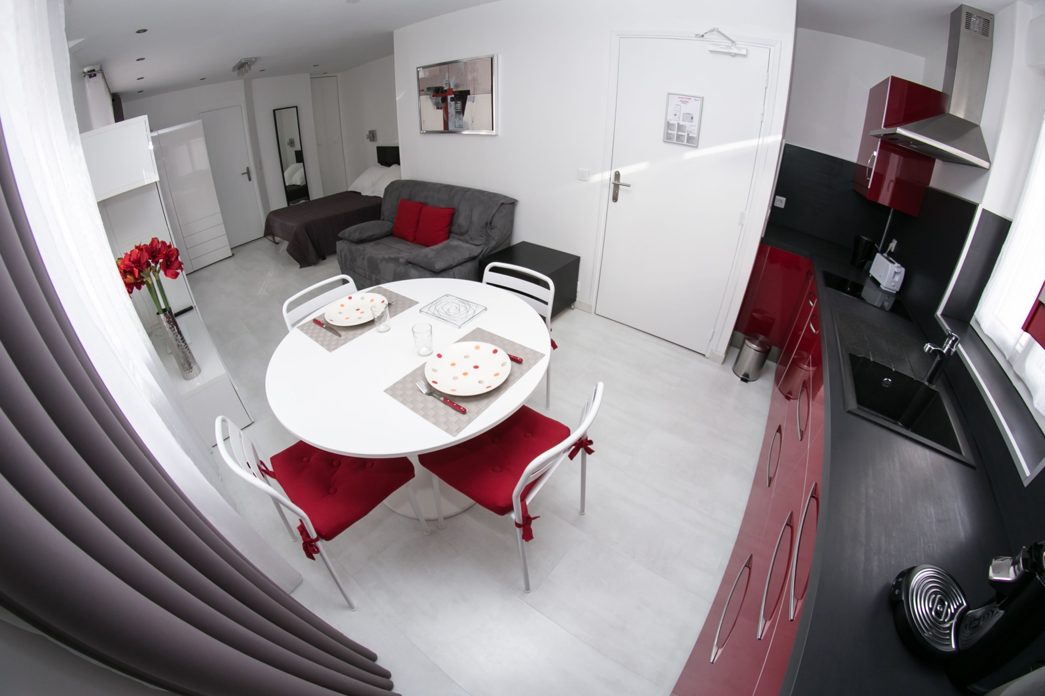 A modern kitchen with a dining area, a sofa, and a small dining table with chairs.
