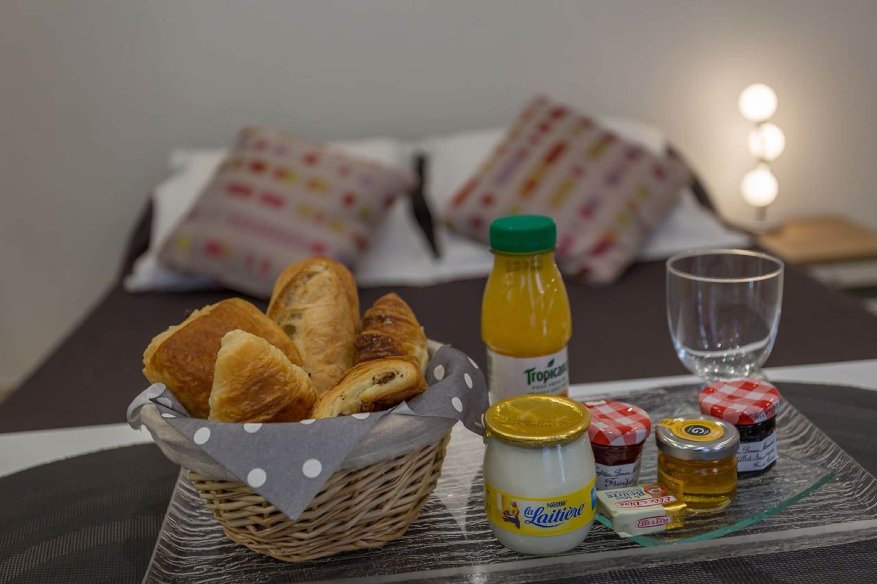 A breakfast setup with croissants, a bottle of orange juice, and condiments on a tray.