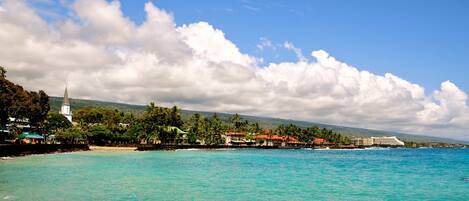 A coastal resort with a beach, a church, and a cruise ship docked.