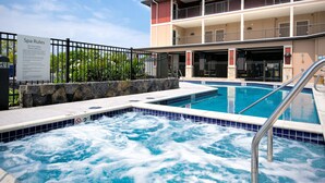 Un hotel con zona de spa que incluye una bañera de hidromasaje y una piscina.