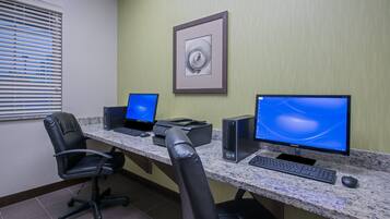 A workspace with two desktop computers, a printer, and a chair.