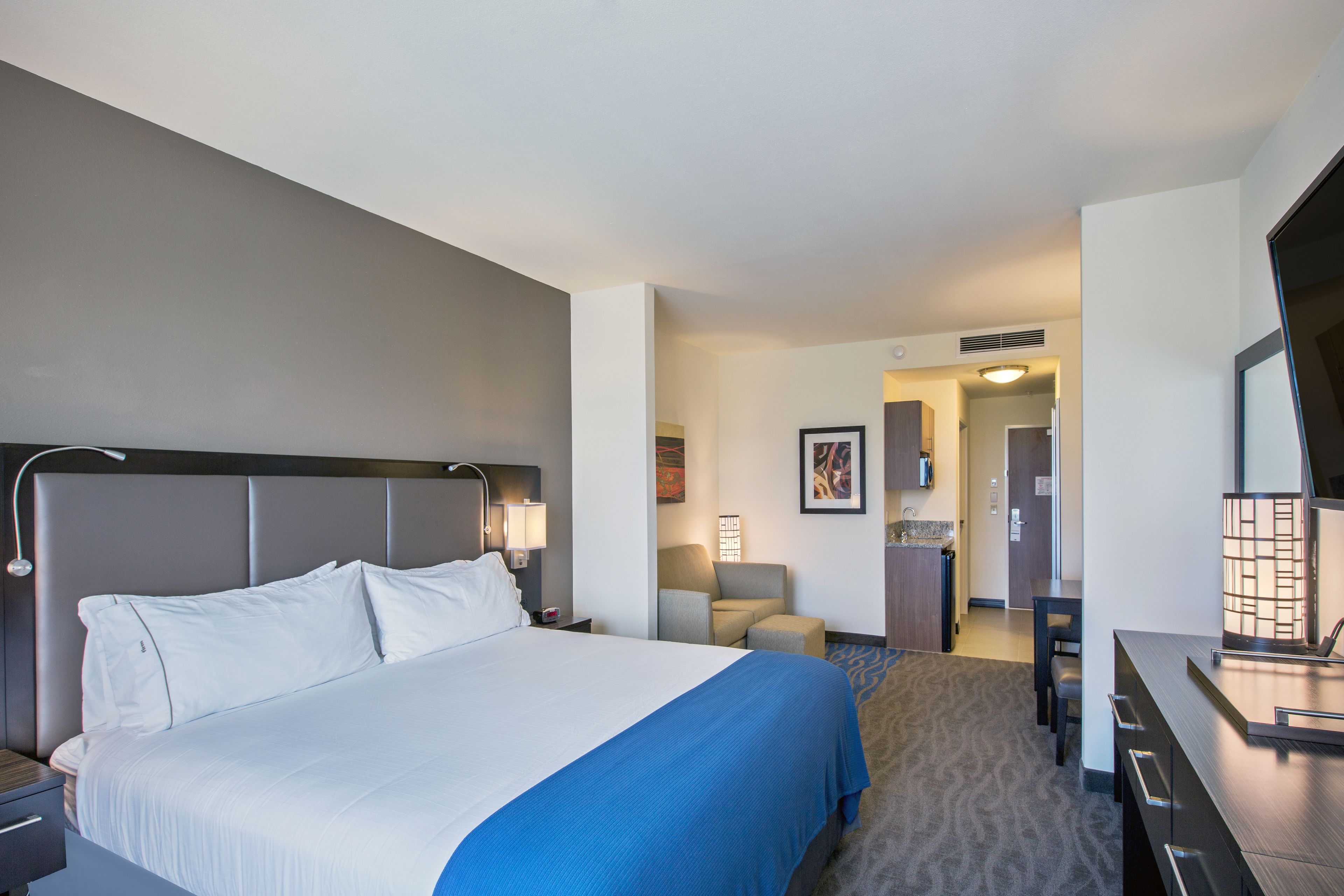 Une chambre d’hôtel avec un grand lit, un bureau, une chaise et une petite table.
