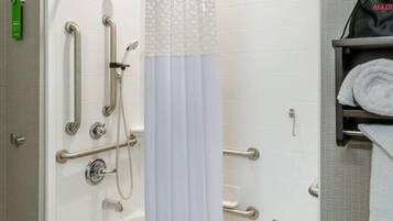 A bathroom with a shower, grab bars, and a towel rack.