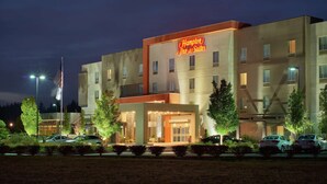 A modern hotel with a prominent neon sign, multiple floors, and a parking lot. - Hampton Inn & Suites Portland/Vancouver (Vancouver)