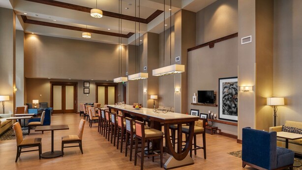A spacious hotel lobby with a long reception desk, multiple seating areas, and a large wall-mounted television. - Hampton Inn & Suites Portland/Vancouver (Vancouver)