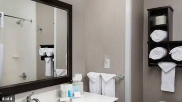 Un baño con un espejo grande, un lavabo y un perchero con toallas dobladas cuidadosamente.