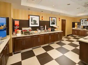 A kitchen with a checkered floor, wooden cabinets, and various appliances.