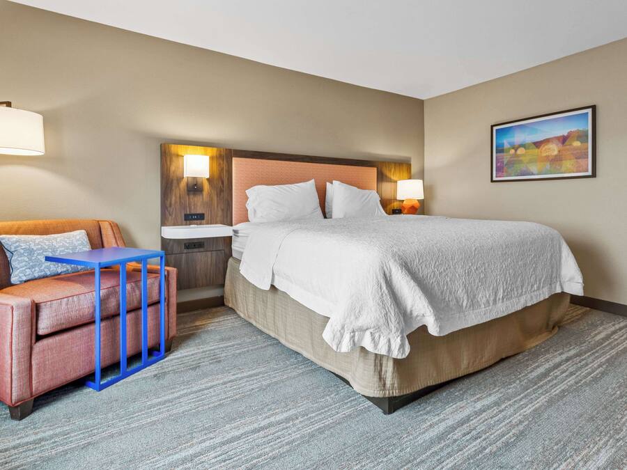 Une chambre d’hôtel avec un lit, un canapé, une petite table et un tableau au mur.