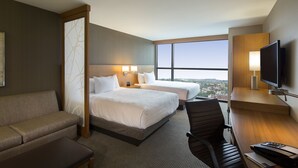 A hotel room with two beds, a sofa, a desk, a TV, and a large window offering a city view. - Hyatt Place Washington DC/US Capitol (Washington)